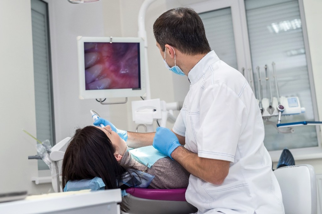 dentist using a camera to look inside patient mouth